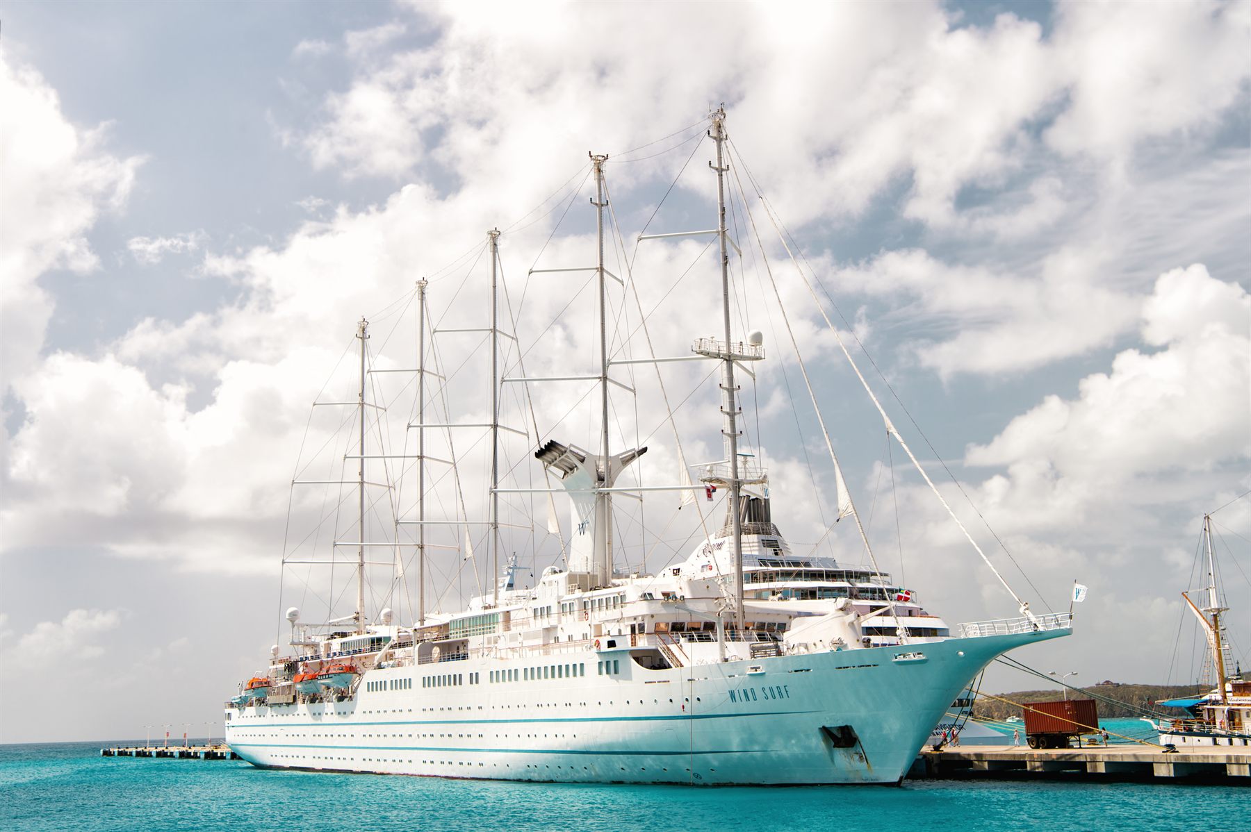 Windstar’s five-masted sailing ship Wind Surf docked at a pier in turquoise water